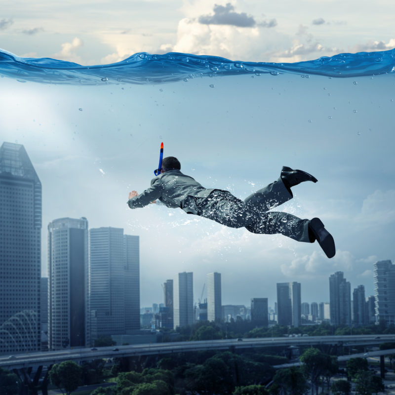 Ein Mann taucht durch eine überschwemmte Stadt